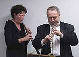 Eine Frau und ein Mann spielen ein Blasinstrument