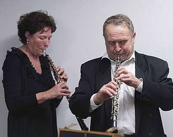 Eine Frau und ein Mann spielen ein Blasinstrument
