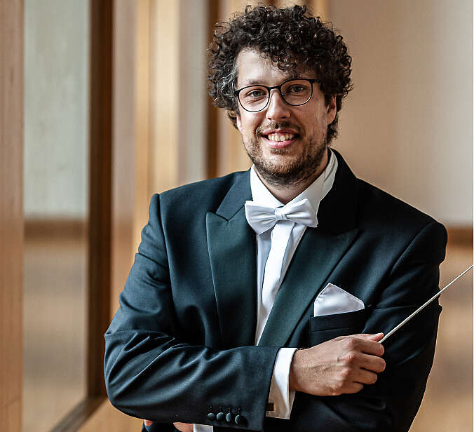 Pietro Sarno in Anzug mit Fliege und Taktstock schaut in Kamera