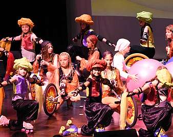 Kinder in Kostümen und mit Einrädern auf der Bühne